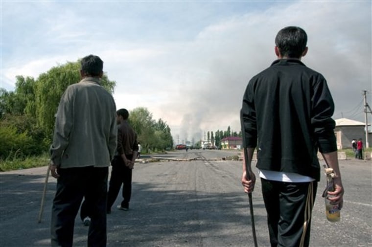 Members of the ethnic Uzbek community armed with sticks and Molotov cocktails look at smoke rising from the burning Uzbek villages set on fire by Kyrgyz attackers near Osh, southern Kyrgyzstan, on Saturday.